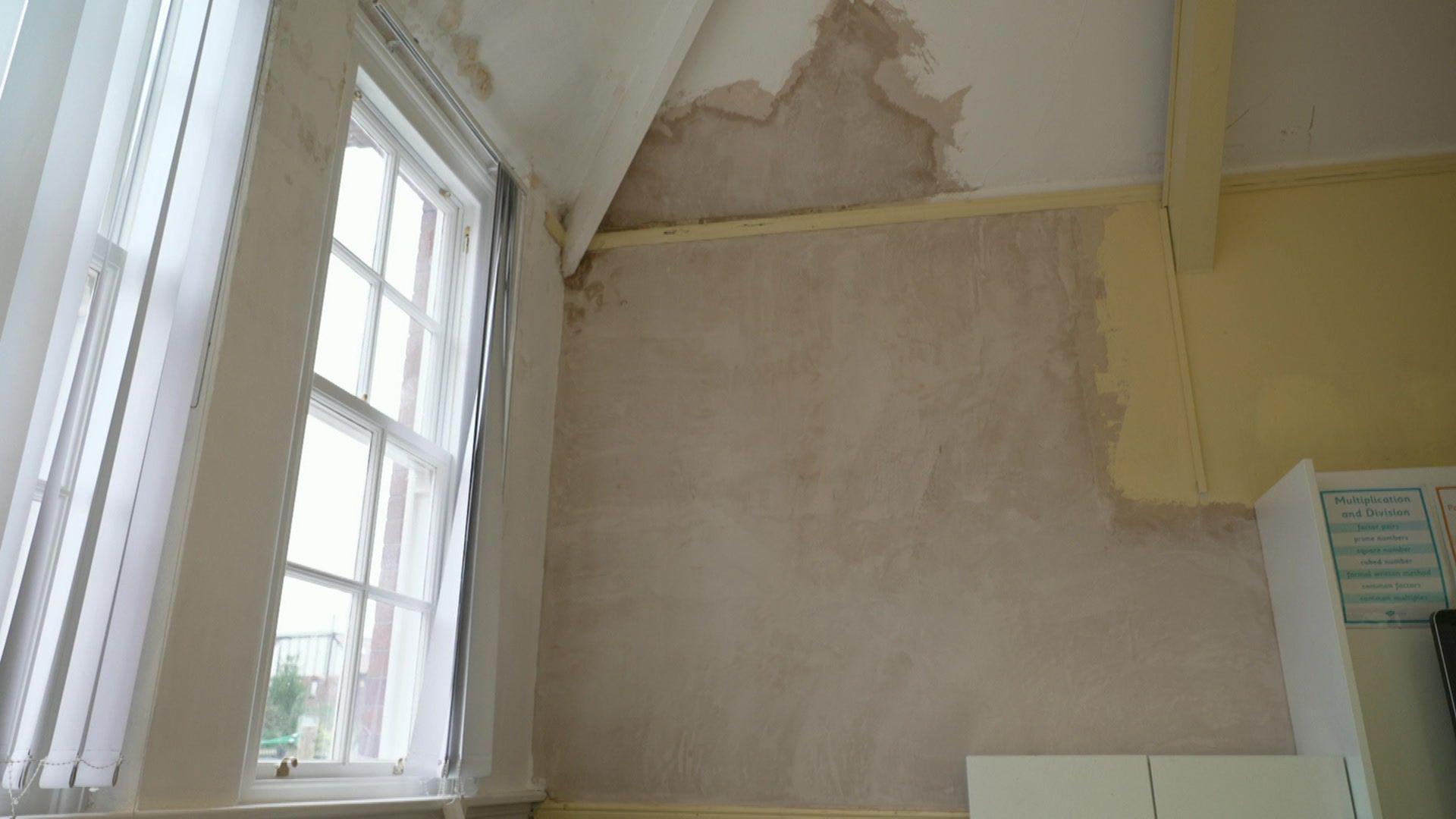 A large white wall which has recently been plastered, with a large white window next to it