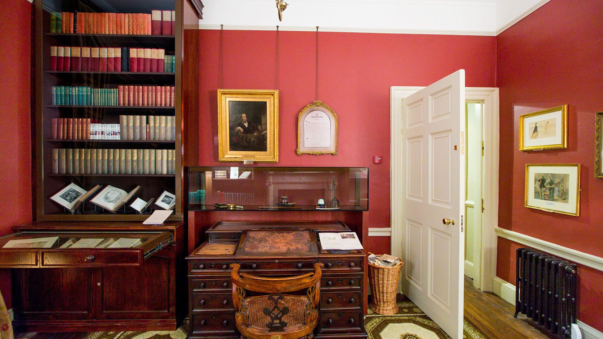 A study, with red walls and dark brown furniture, including a desk and book case