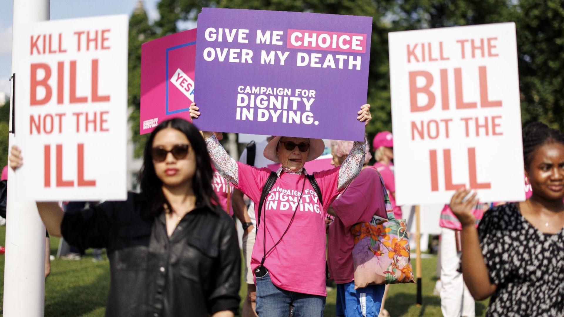 Campaigners on both sides of the assisted dying debate hold up placards outside Parliament in June 2025. One reads: "Kill the bill not the ill", while another reads: "Give me choice over my death".