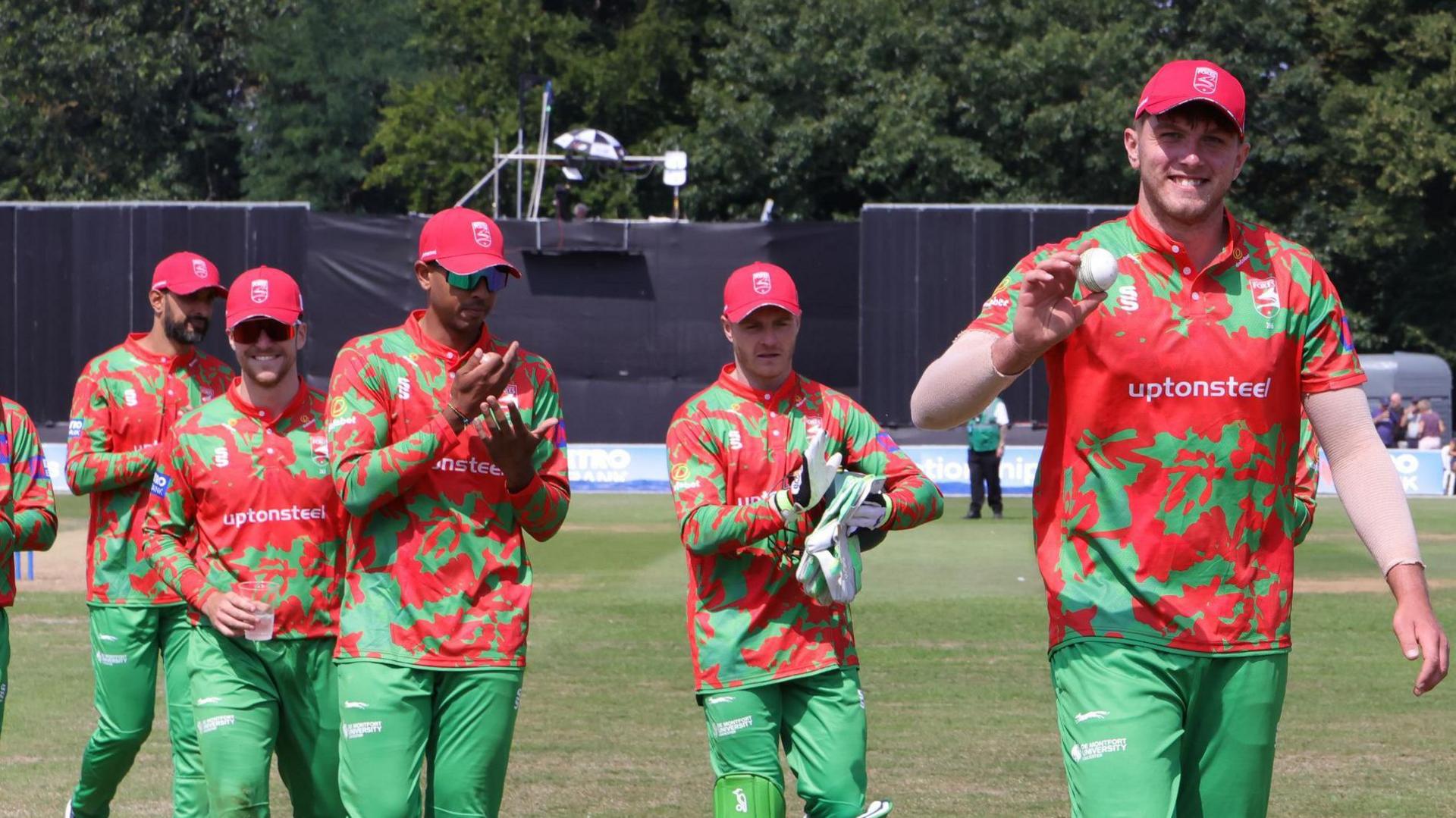 Alex Green (right) leads his Leicestershire team-mates off the field after taking five wickets