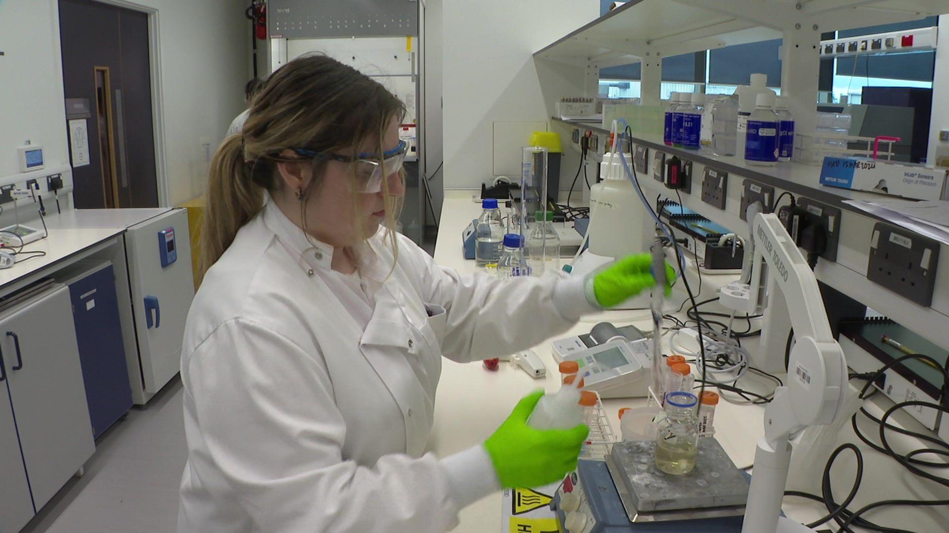 Researcher holding equipment over a beaker inside the cancer research facility