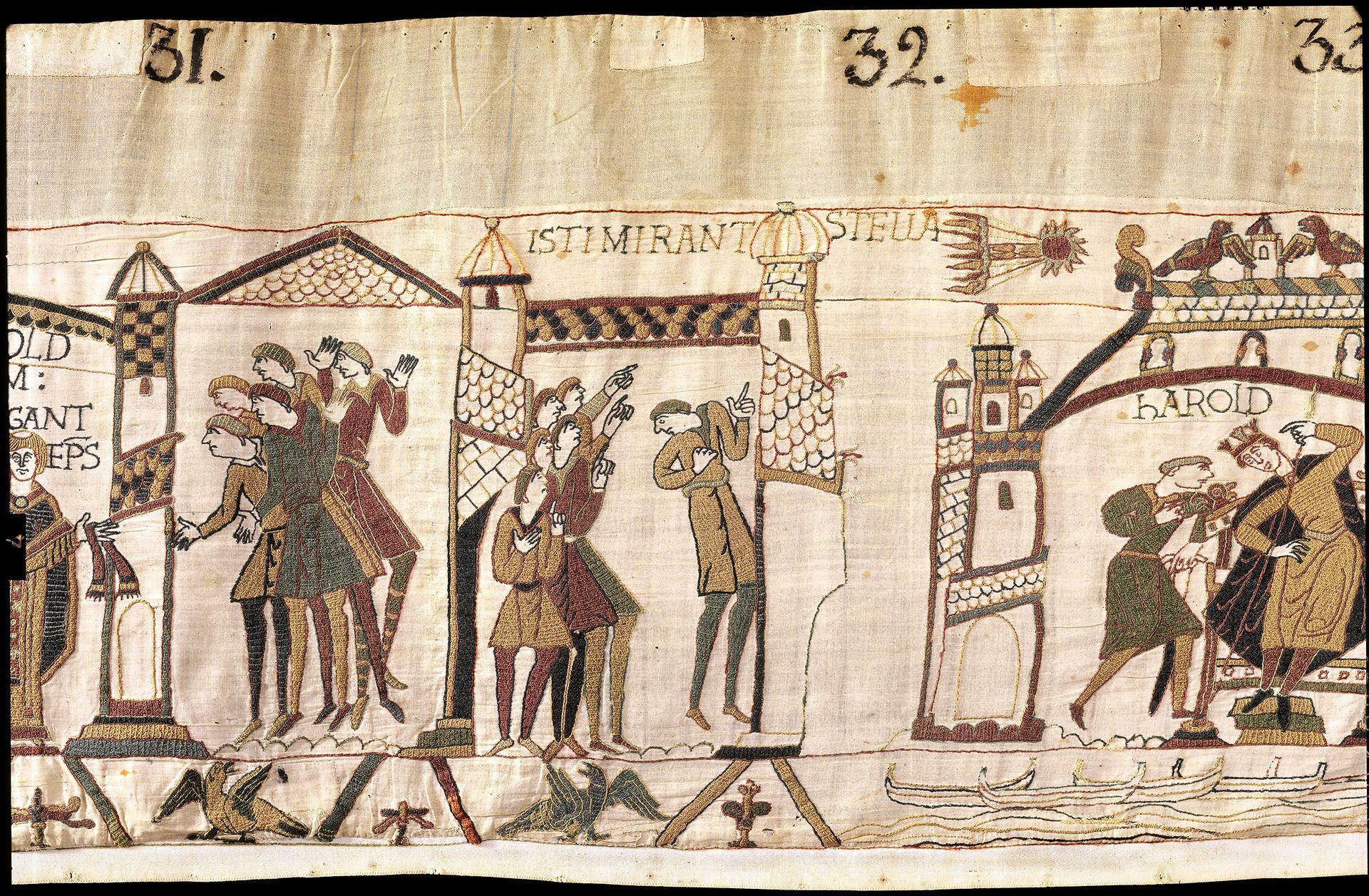 A wide crop shows the scene of people looking up at the sky and pointing while a comet flies above, they are surrounded by medieval buildings, and at the top of the tapestry you can read numbers 31, 32 and 33.