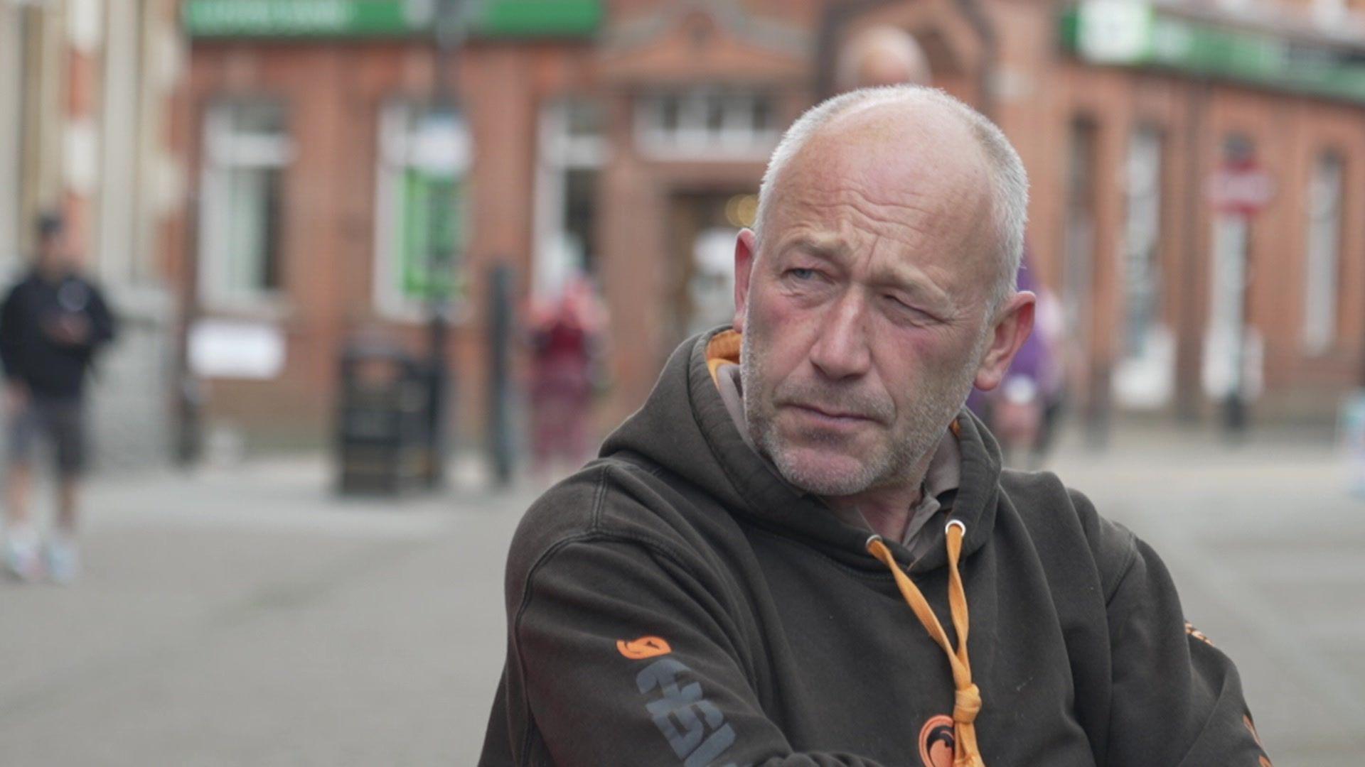 Man in black hoodie from shoulders up, with aldershot out of focus in the background