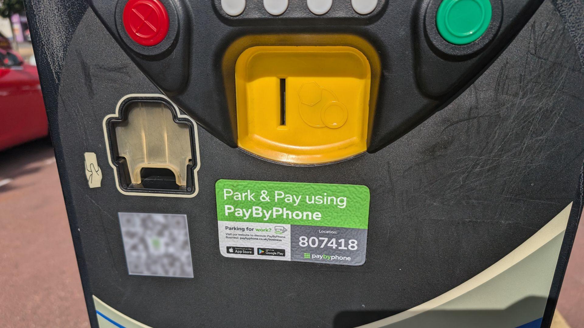 The front of a car park pay and display machine with a QR code sticker attached next to the official signage