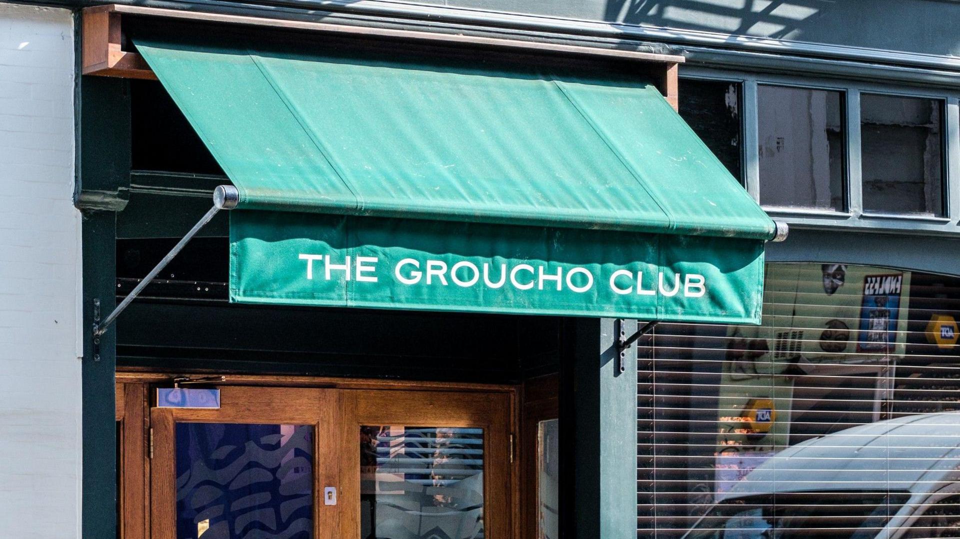 A close up of the exterior of The Groucho Club with a green canopy and white writing with the name of the club on it. 