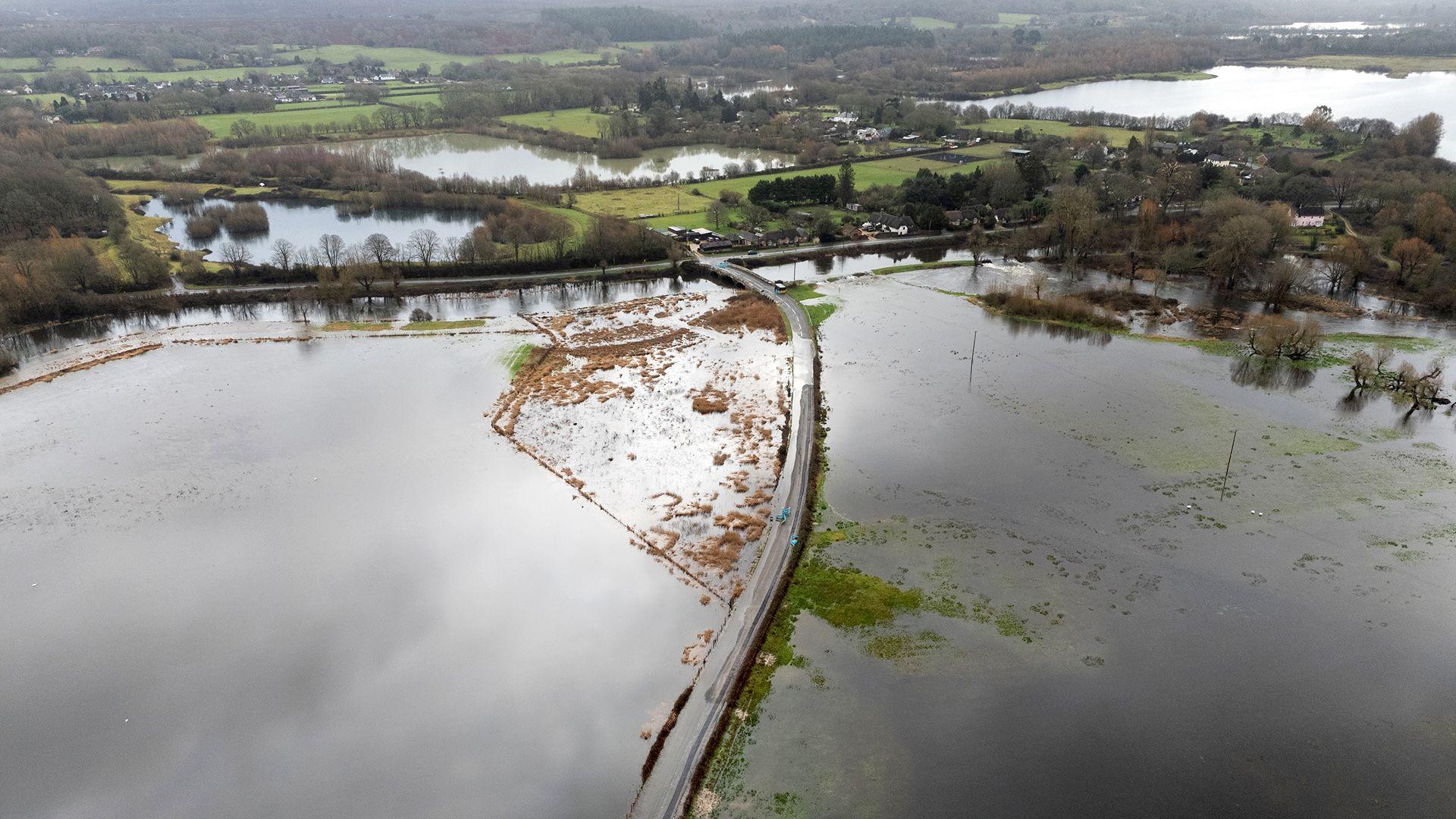 An aerial image shows a flooded road surrounded by standing water in a rural setting with trees, greenery and more floodwater in the background, in Hampshire on Friday.