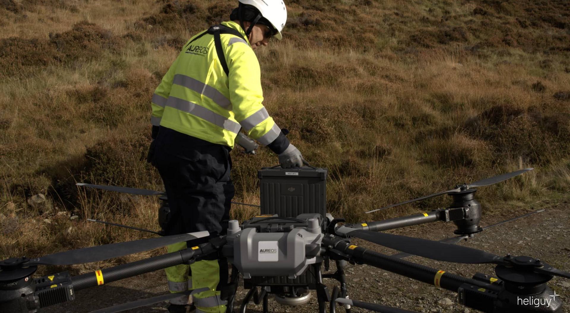 Fear-obrach le seacaid bhuidhe agus clogaid air ri taobh dròna air an talamh
