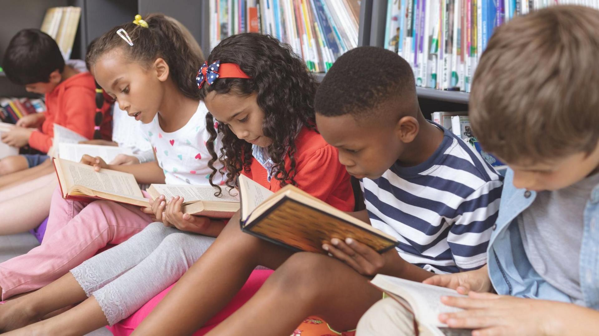 Children sat in a row reading books