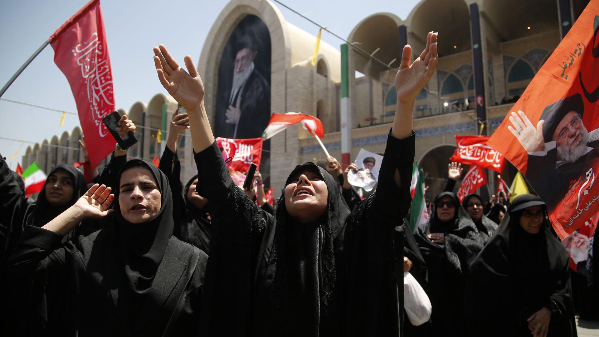 Iranians gather to grieve, with one woman crying up to the sky with her arms stretched up