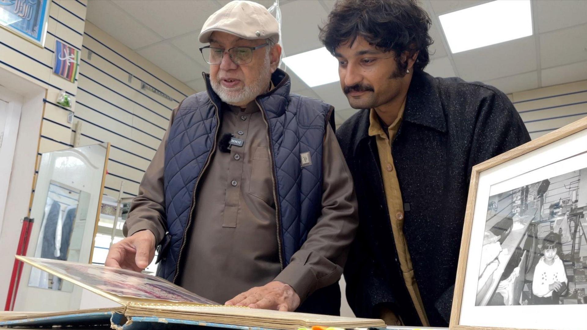 Barket and Zain look through old a photo album of Nayyir Garments through the years.