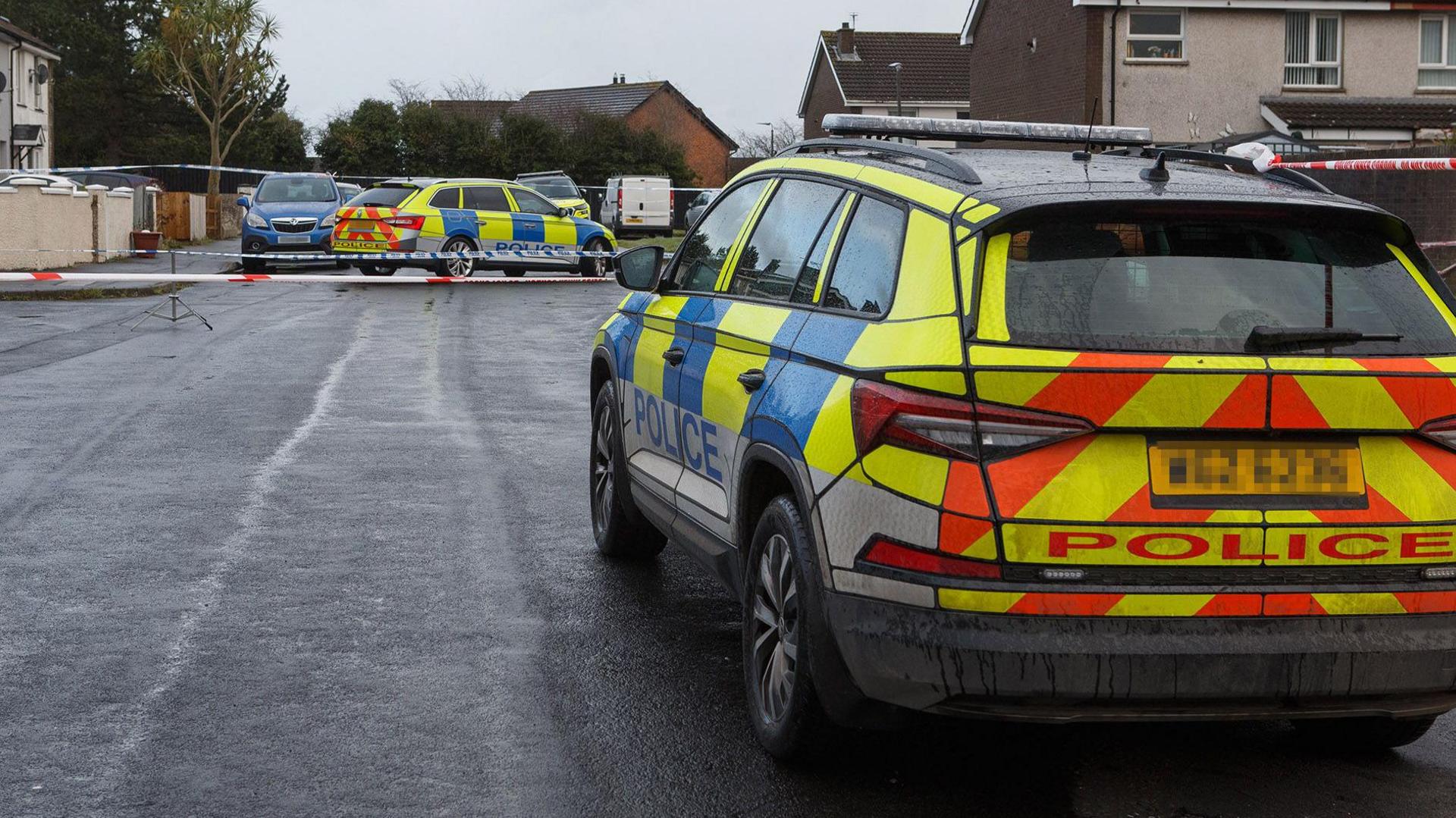 Two police cars are parked in a deserted street. 