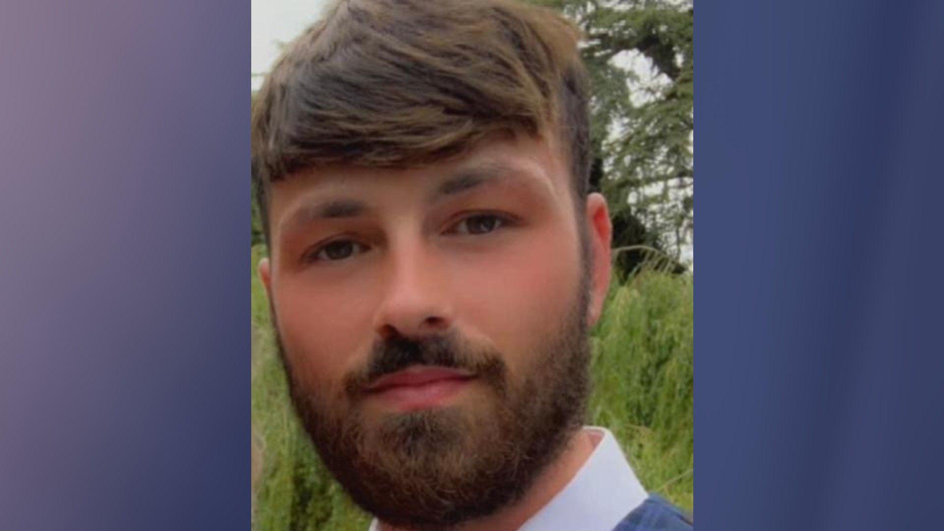 Hayden Mills smiles at the camera while wearing a blue suit jacket and a white shirt