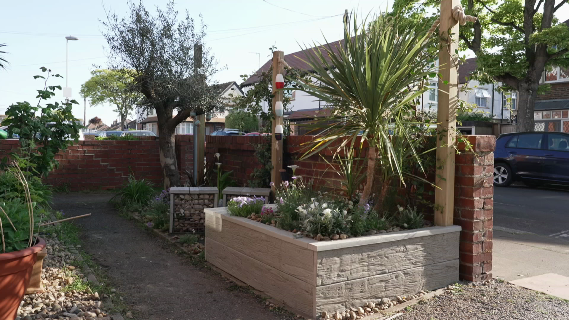 A small outdoor space at the front of a house with a raise gardening bed.
