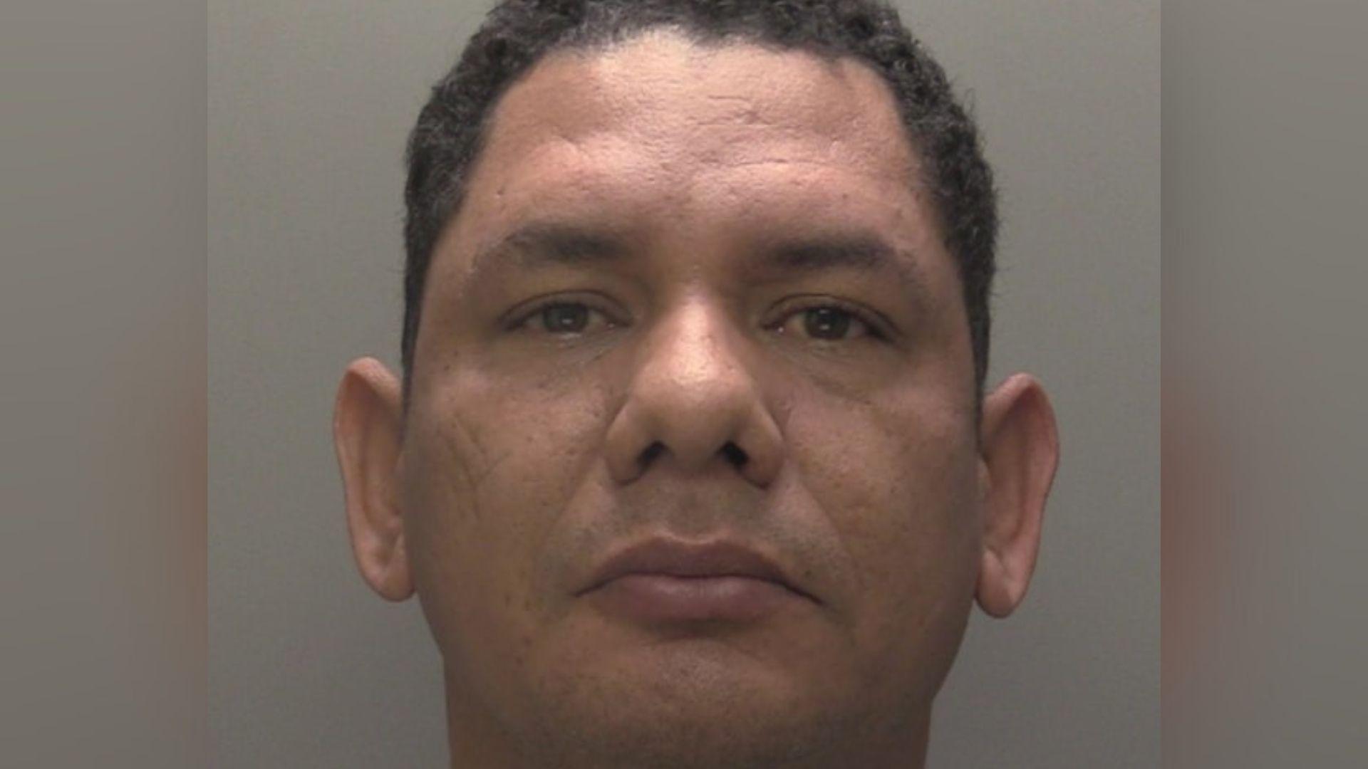 Custody photograph of Didier Reyes  he has short black hair and is wearing a grey T-shirt