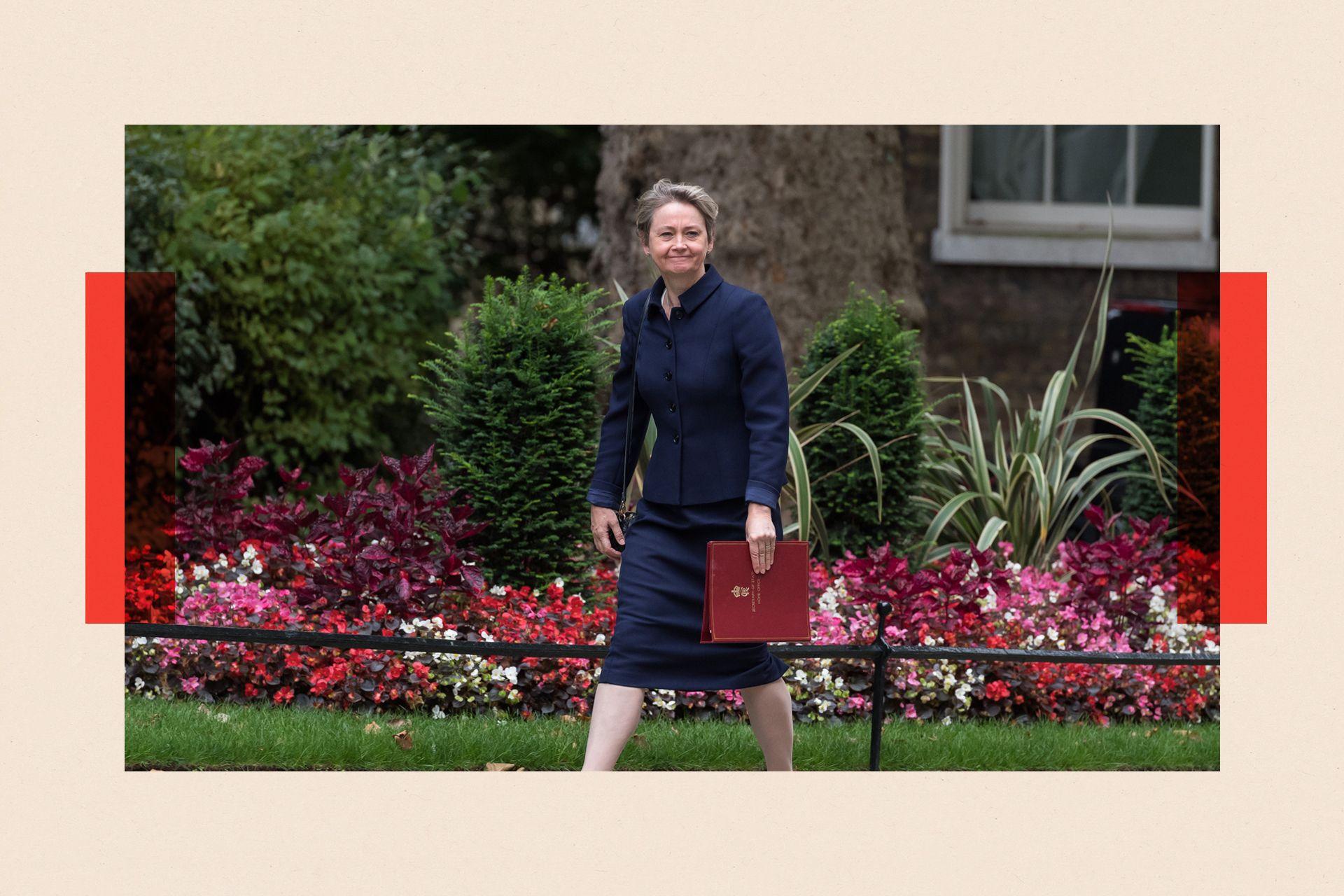 Yvette Cooper walking outside in front of a flower bed
