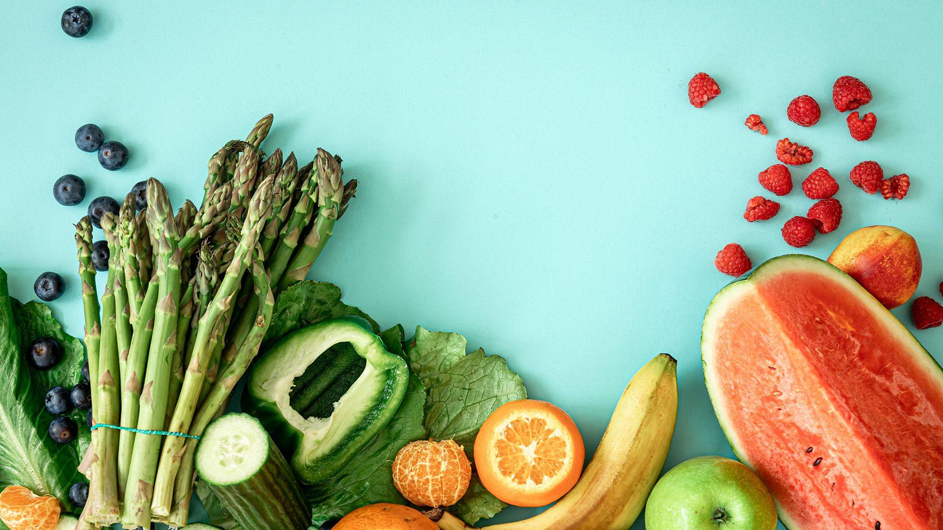 A selection of fresh fruit and vegetables on a light blue background