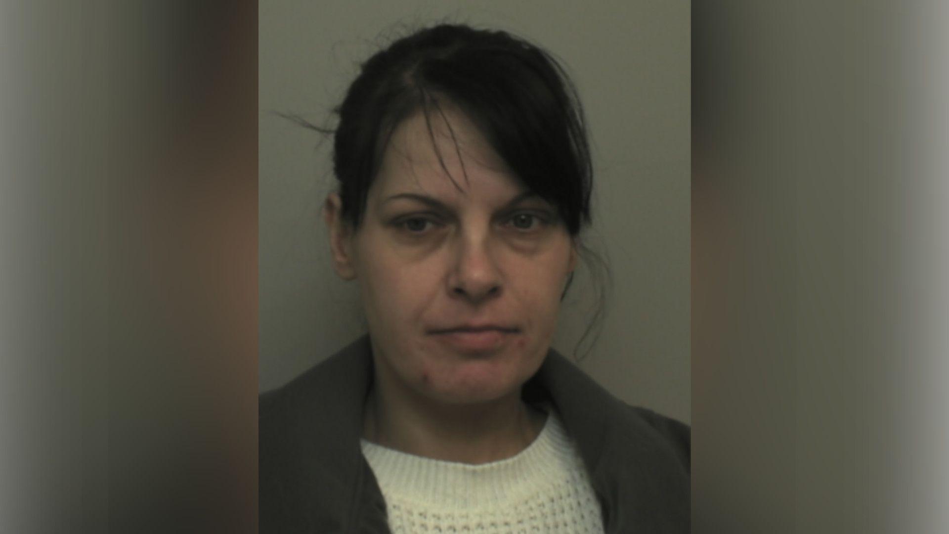 Tracey Makings with medium-length dark hair, a white jumper and a grey jacket, looking at the camera in a police custody photo.