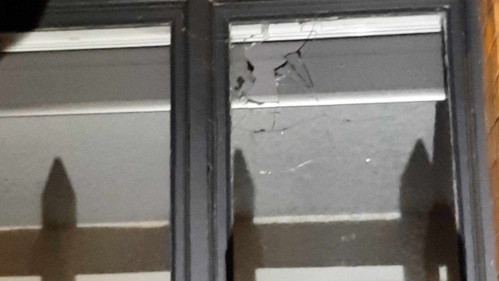 A hole is smashed in the upper right corner of a window, with part of the glass missing. The edge is jagged.