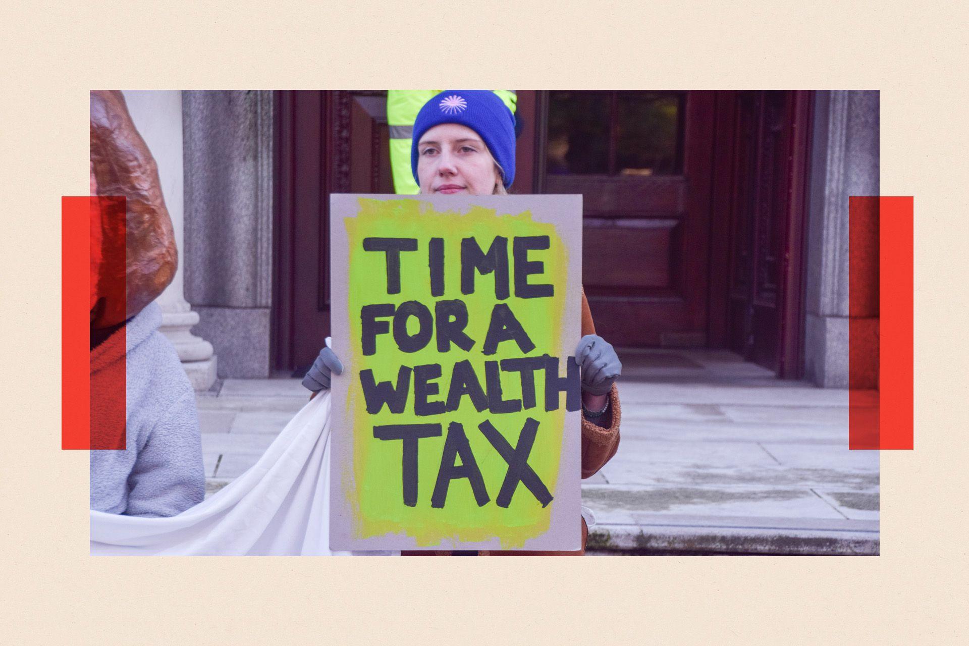 An activist holds a 'Time for a wealth tax' placard