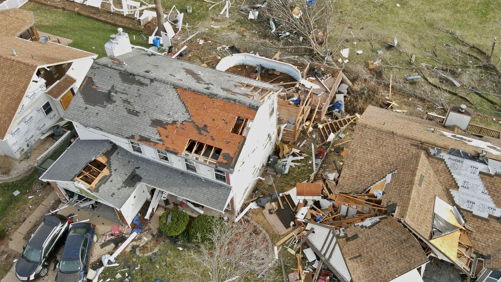 lots of debris surrounding a house after a tornado hit it