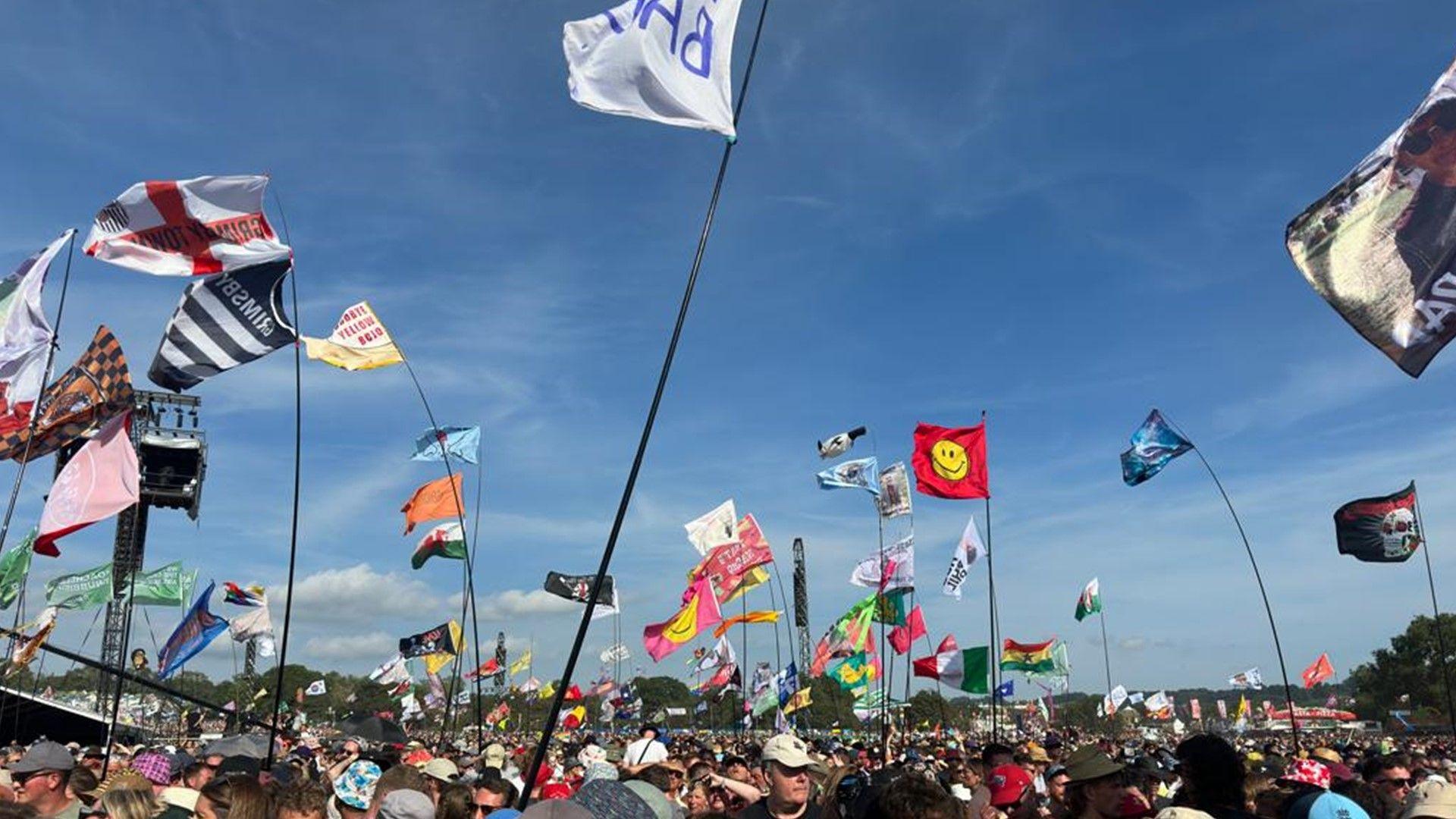 Flags and festival-goers at a sunny Glastonbury