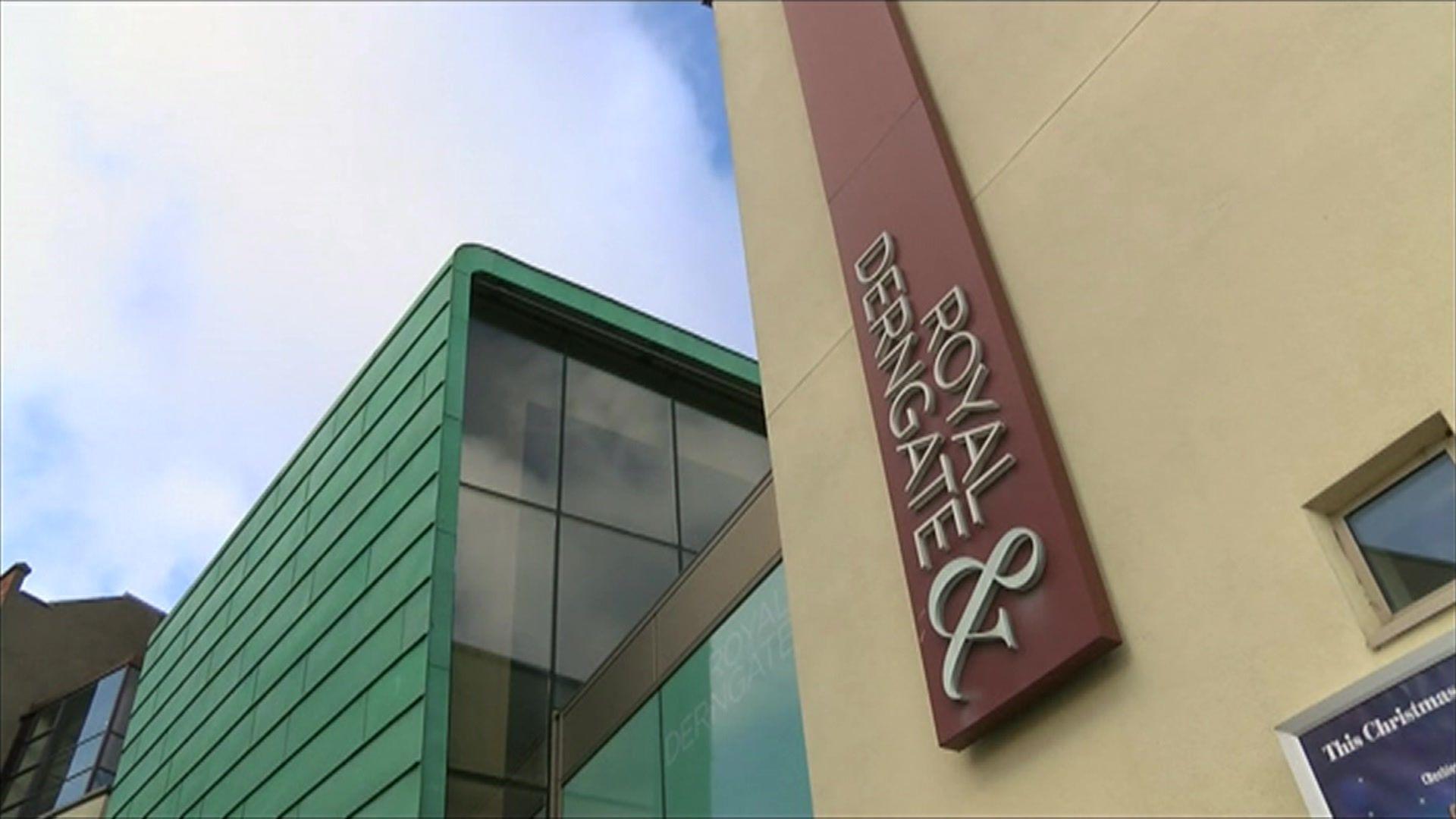 A yellow, green and glass building with a sign in white with a maroon background