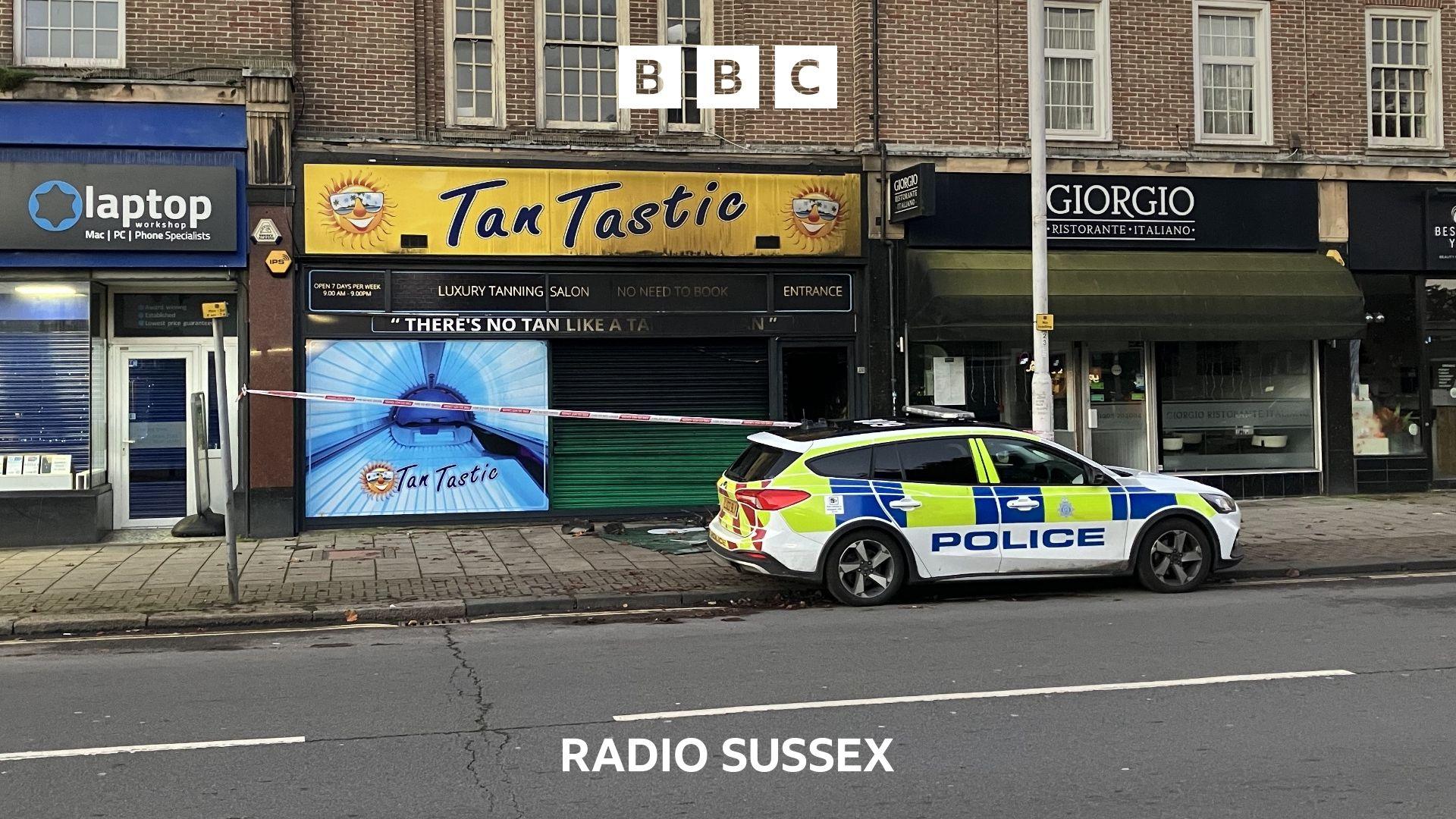 A Police car is parked outside the burnt out remains of the Tan Tastic Salon.