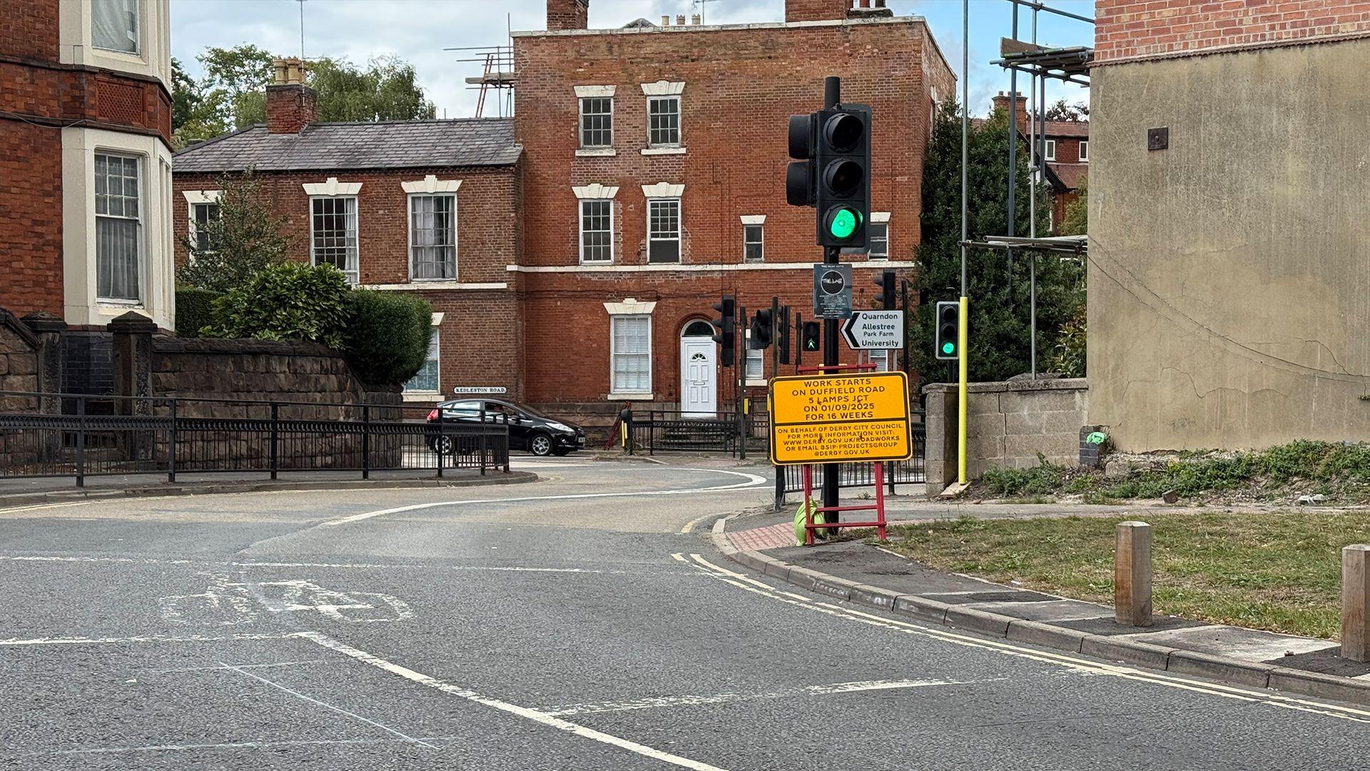 A yellow sign announcing roadworks for 16 weeks on Duffield Road from September 1st next to the traffic junction in Derby