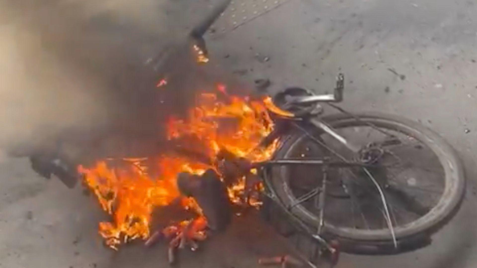 A bike is engulfed in flames whilst on the floor of a train platform. 