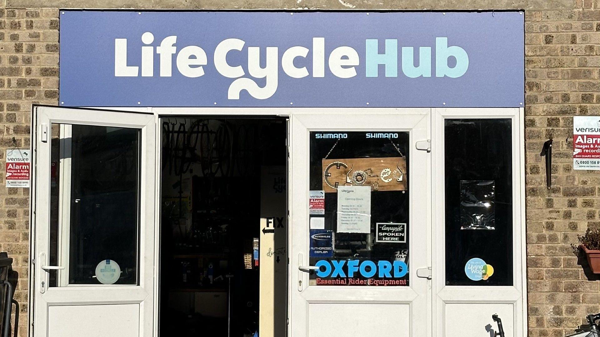 The front of the Life Cycle hub in Derby. It is a brick building with a white front door and a sign saying "Life Cycle Hub"