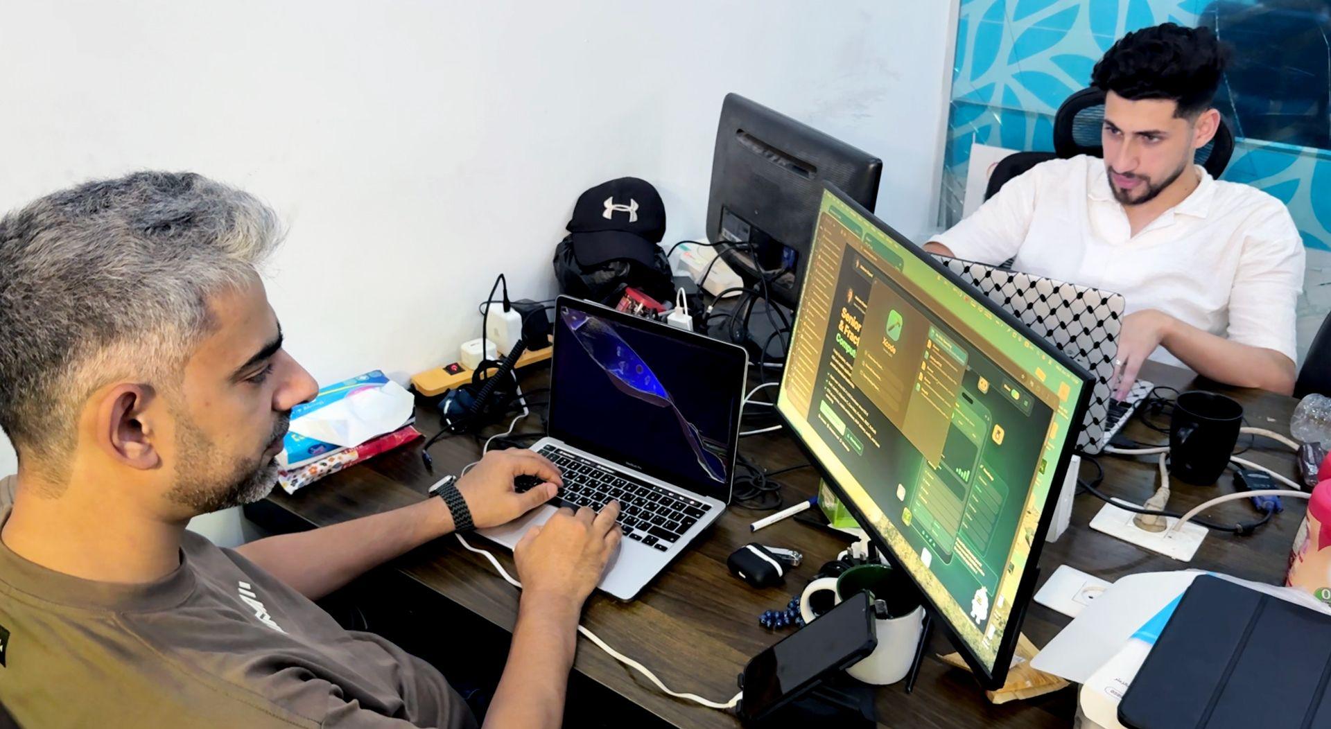 Mahran Bayed works on a laptop with an external display in Gaza