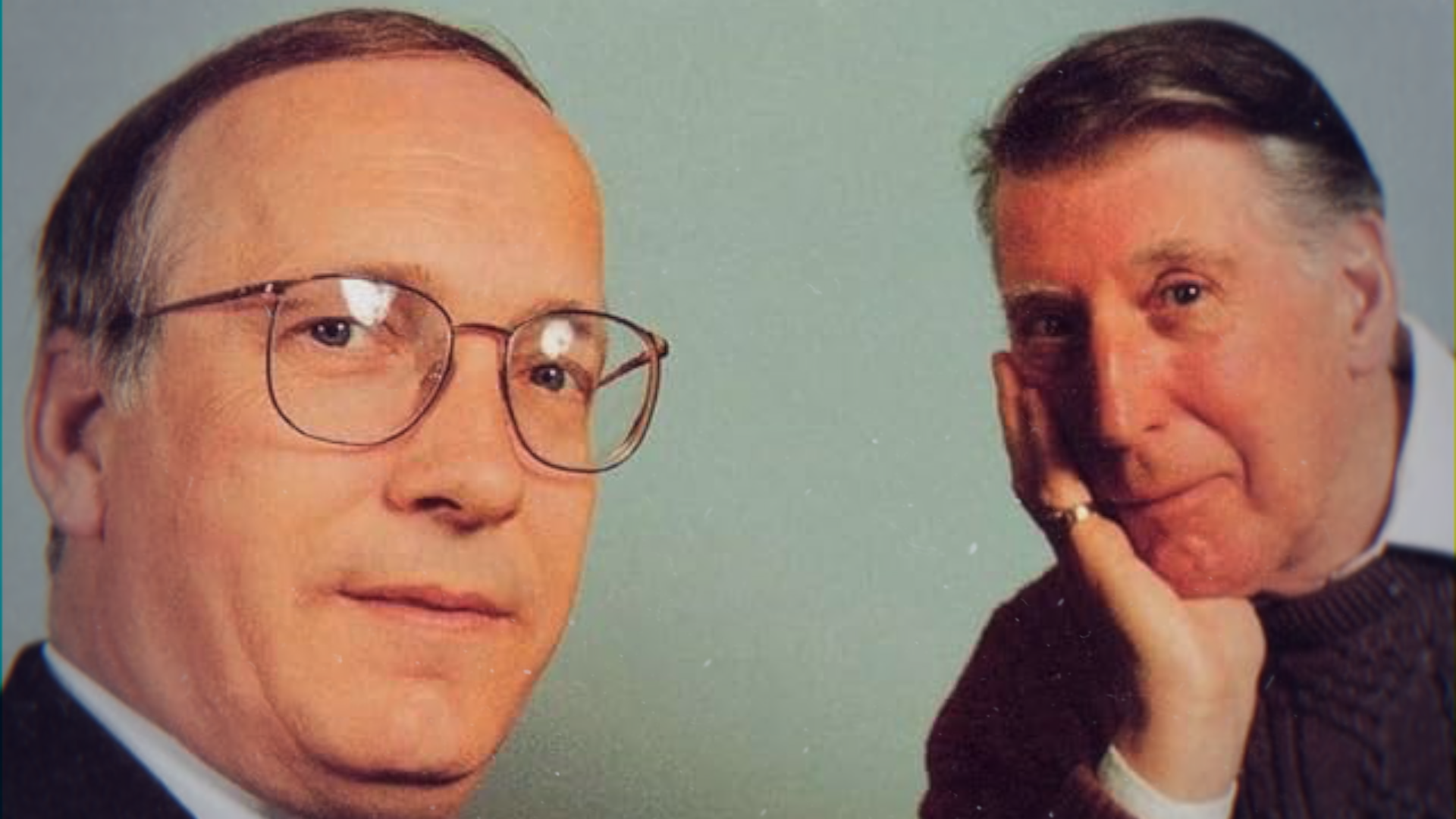 An archive photo of Rev Symington, a man with a grey and black combover wearing thick glasses and Rikki Fulton who is leaning on his hand wearing a burgundy sweater with a shirt underneath.