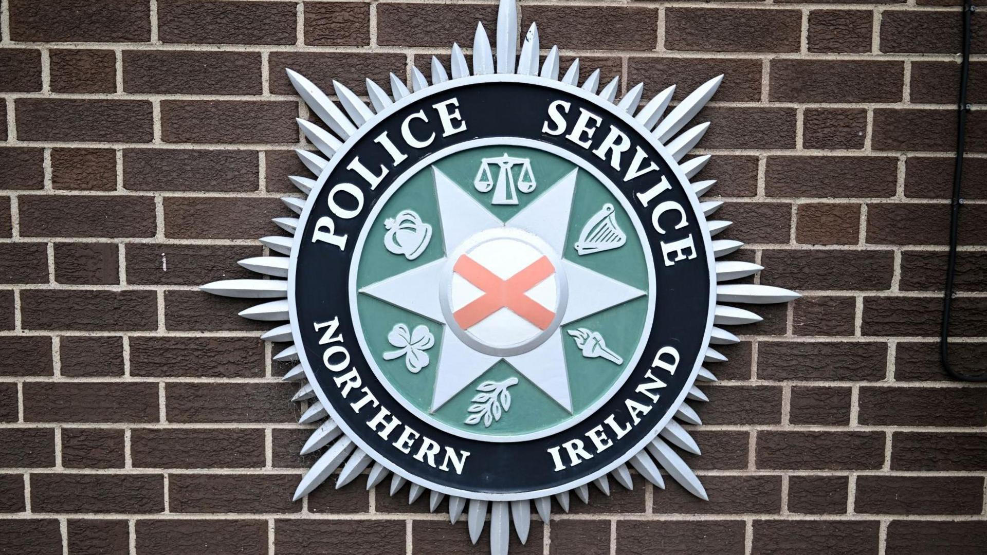 The Police Service of Northern Ireland crest on a brown brick wall