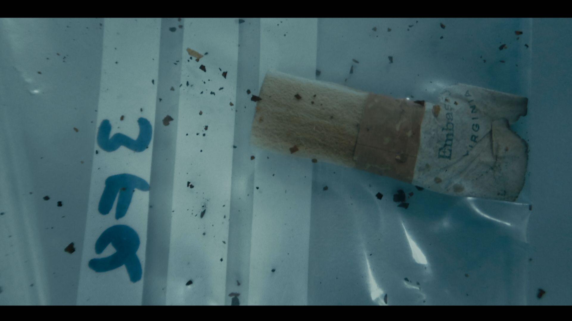 Close up of a clear plastic evidence bag containing an Embassy cigarette stub.