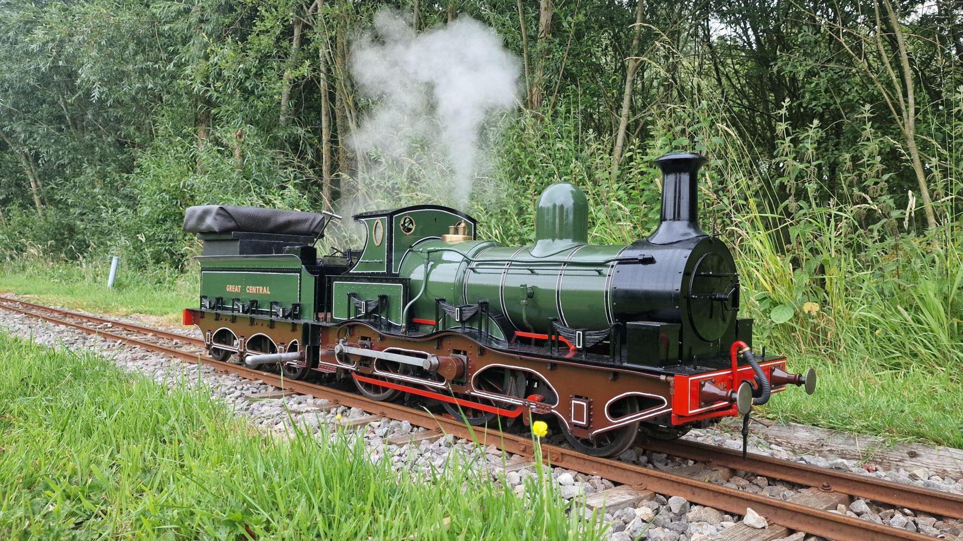 A miniature steam locomotive painted in dark green and black