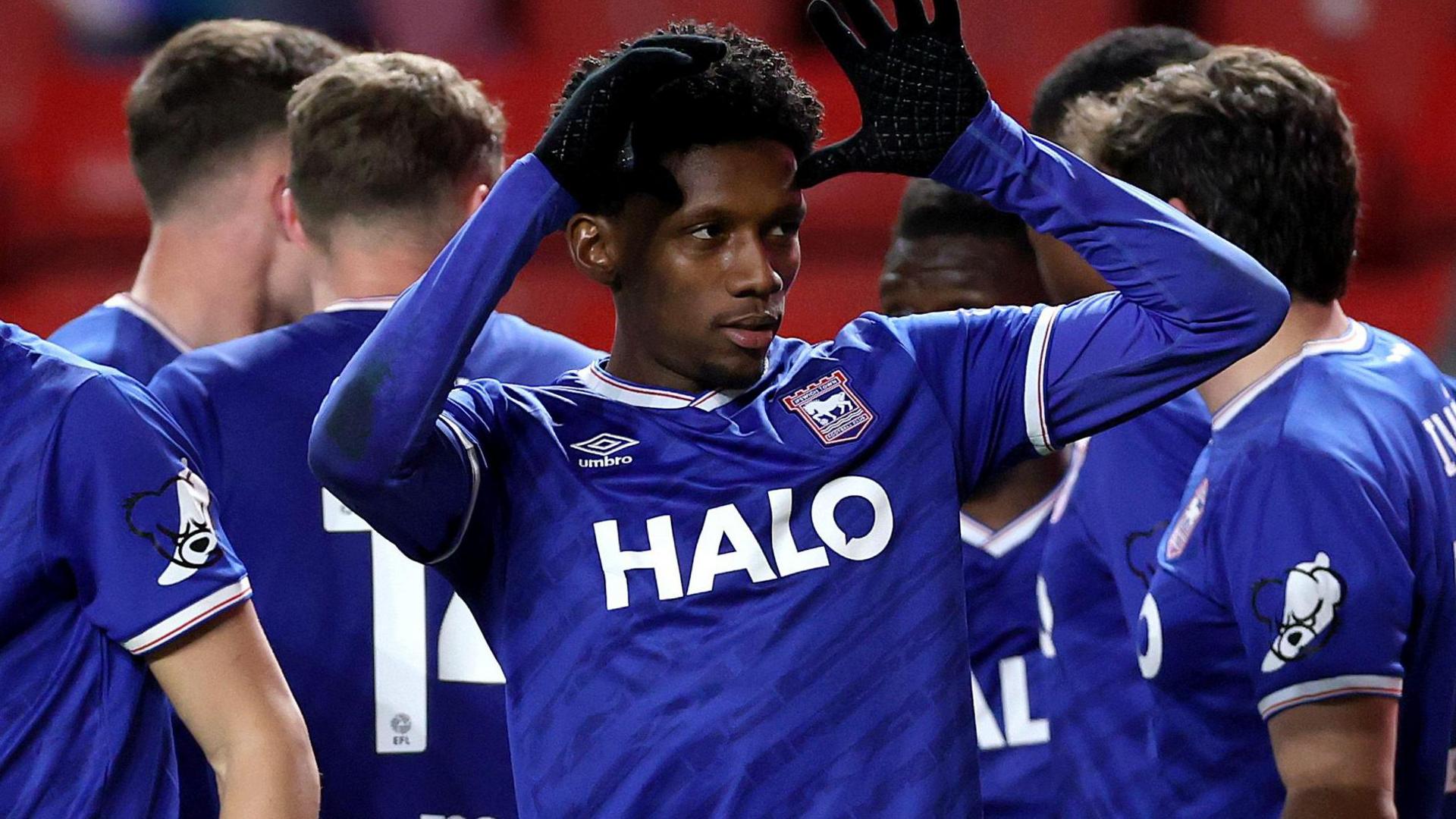Jaden Philogene, wearing Ipswich's blue home shirt, puts his hands by his head to celebrate the winning goal at Charlton