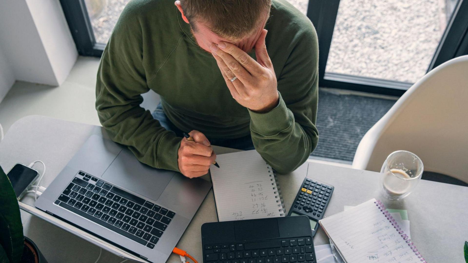 man working out bills with head in his hands