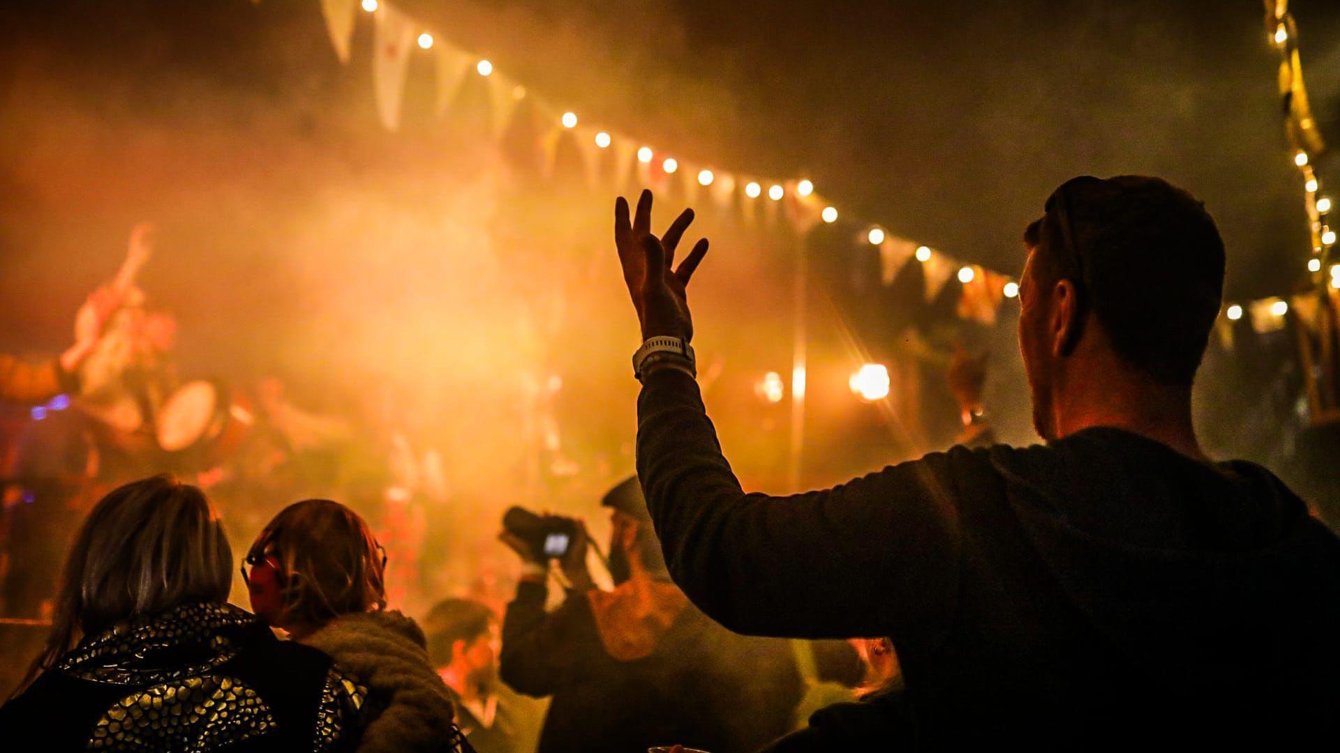 People watching a band in a tent with bunting up