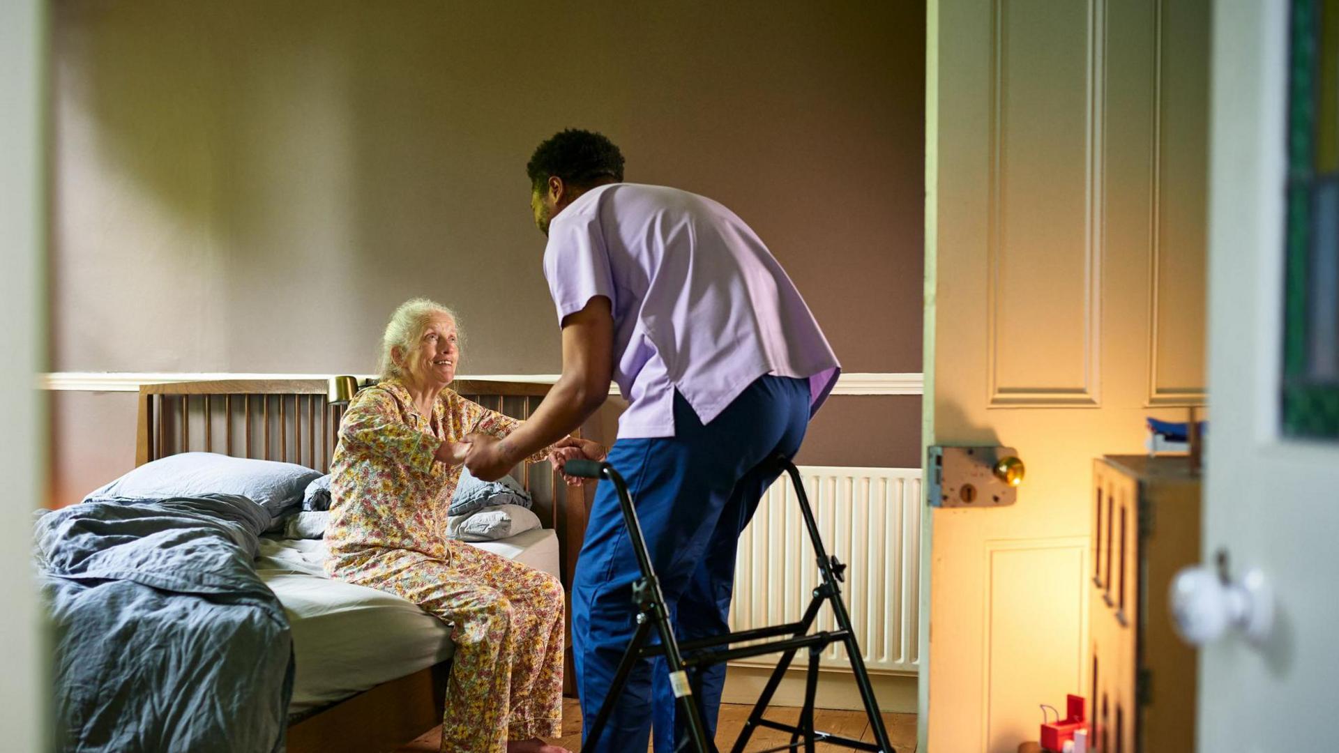 Stock image of a carer helping a woman out of bed in a care home