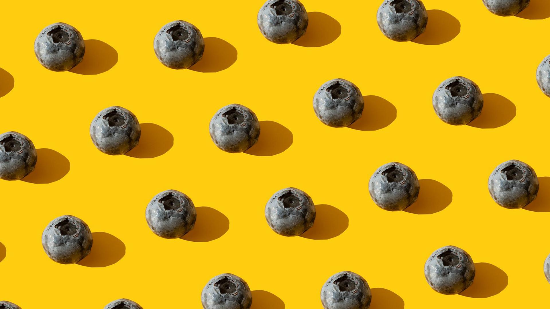 Closeup of blueberries lined up on a yellow background