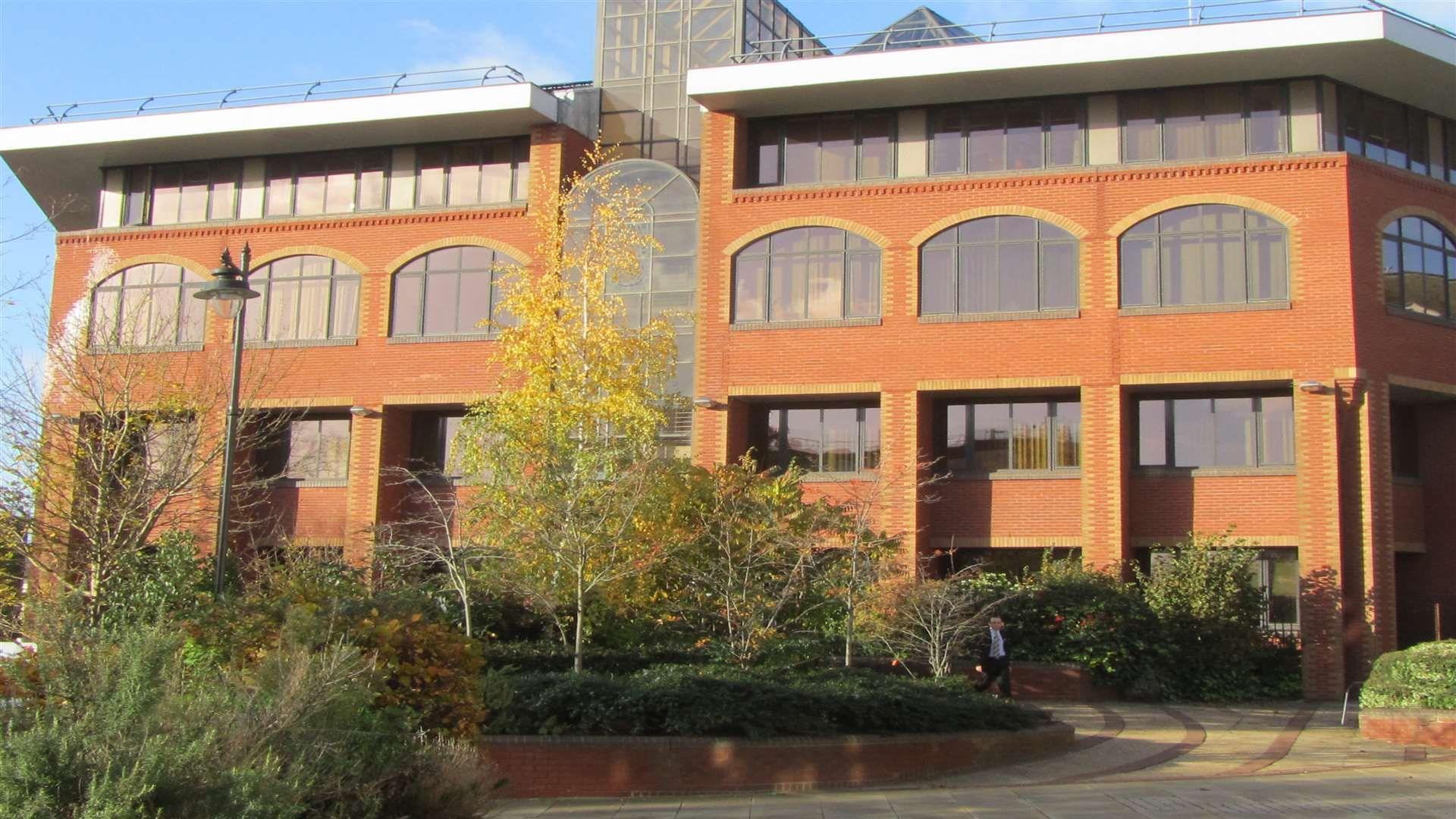 A building with a red facade and trees in front of it.