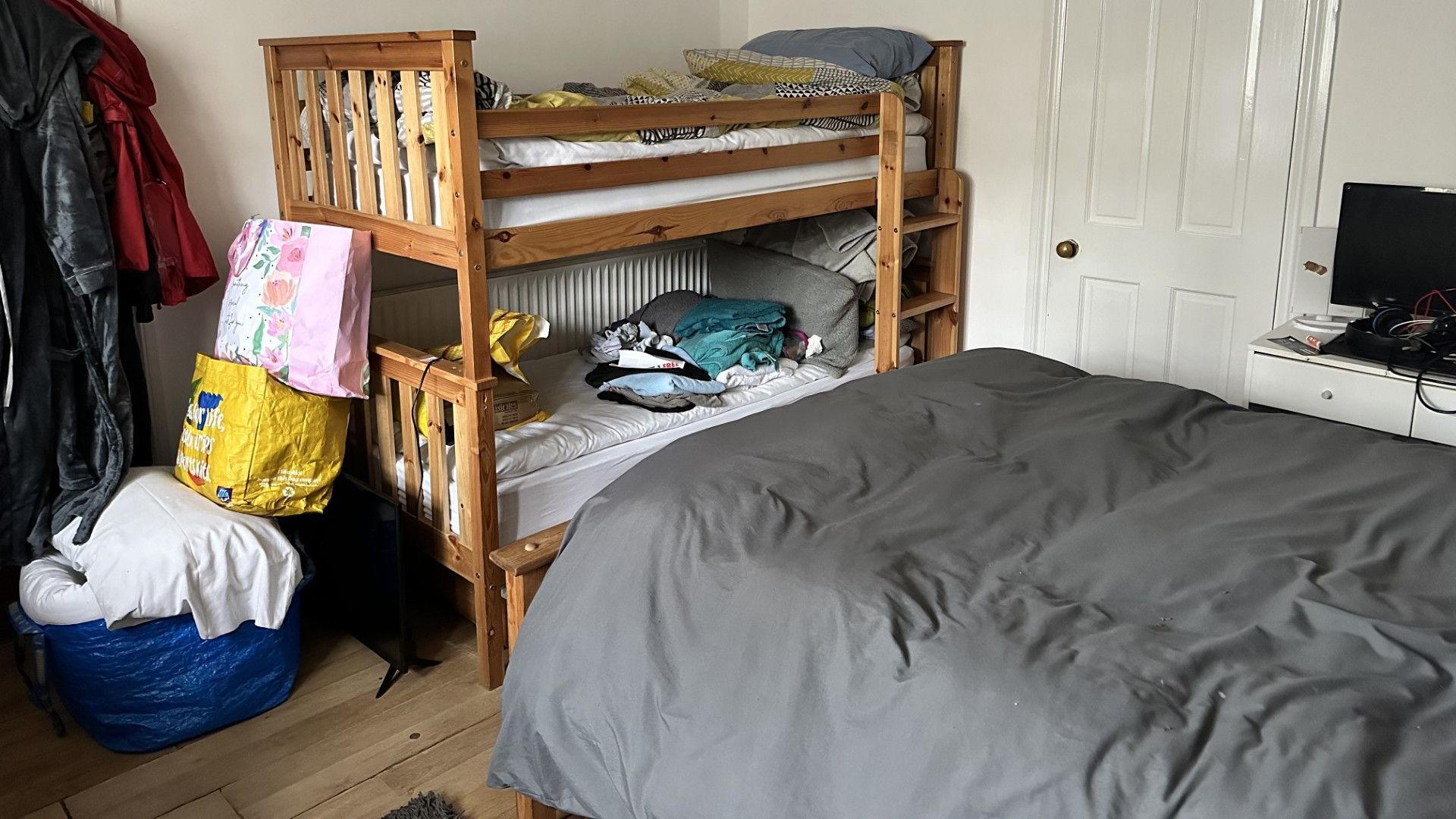 A cluttered room filled with bags and bunk beds.