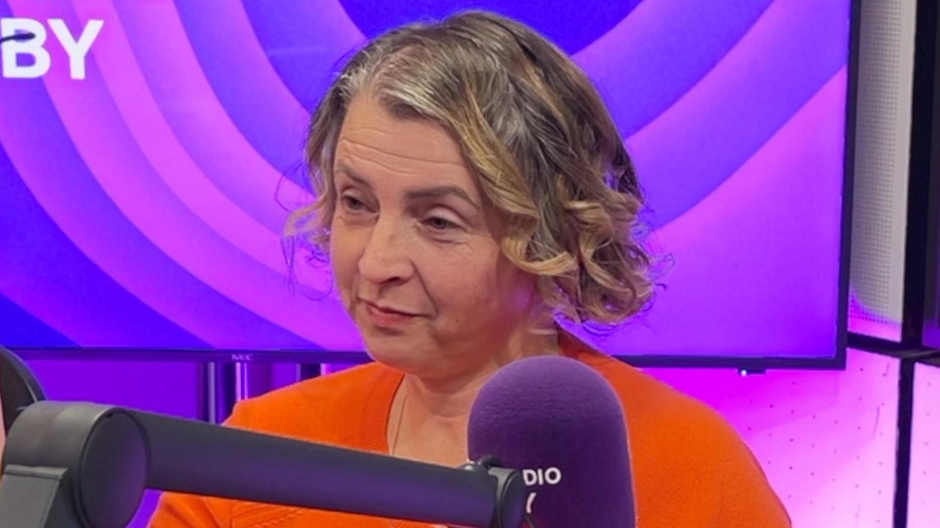 Picture of Agnes Adkins in the BBC Radio Derby studio. She is wearing a red top and has a fair-coloured bob haircut.