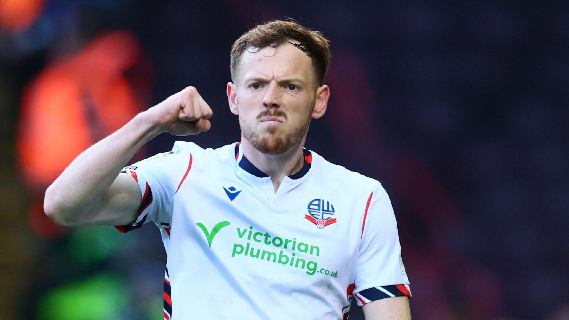 George Johnston punches the air in celebration during a match for Bolton Wanderers.