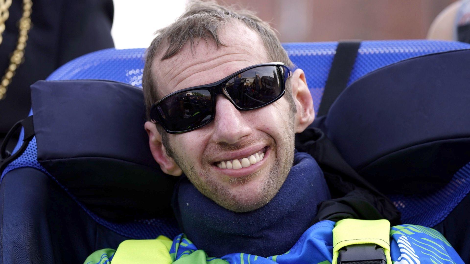 Rob Burrow, wearing a green and blue top with black sunglasses.