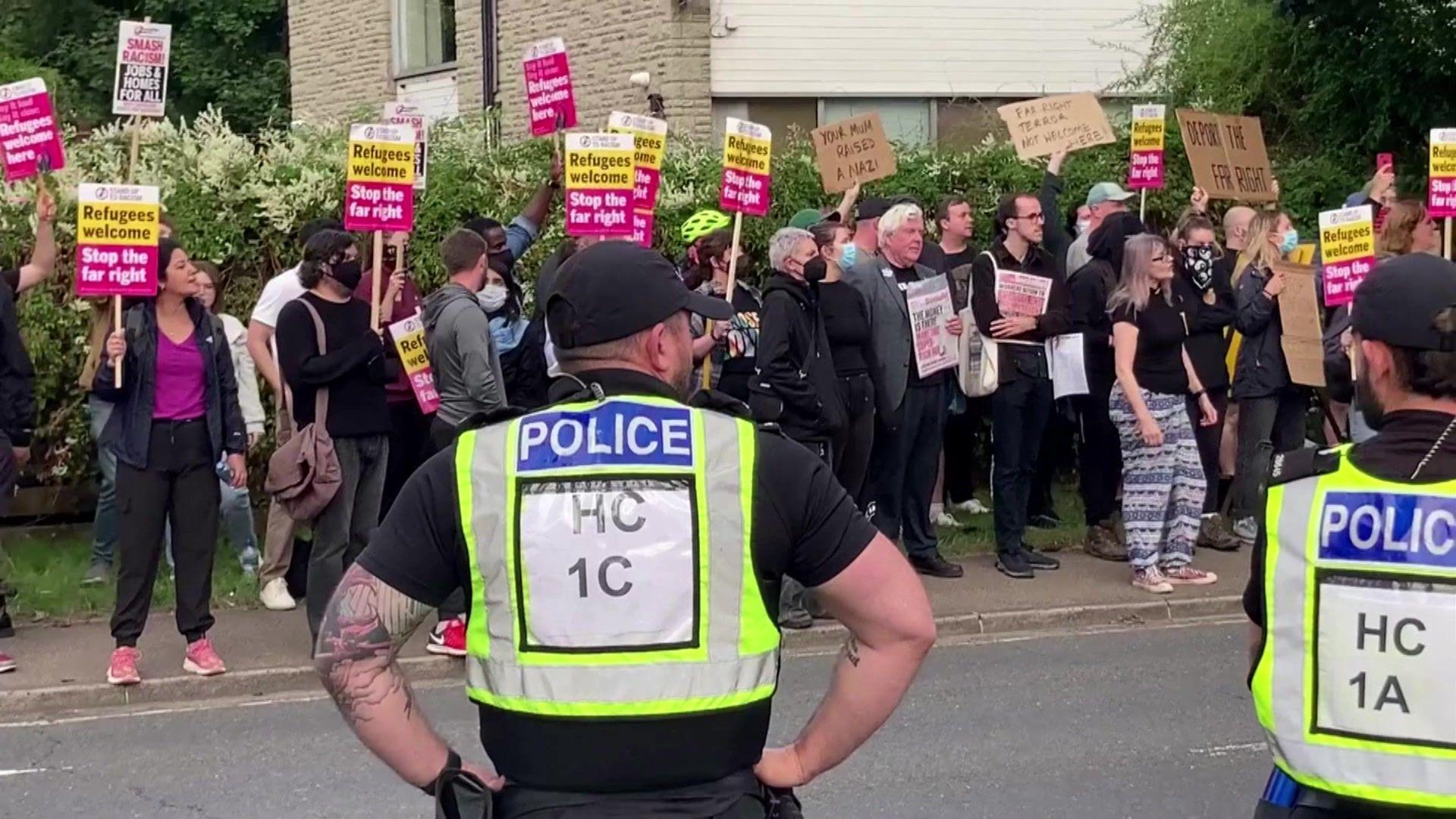 Anti-racism campaigners on one side of the road but two police officers facing them, with their backs to the camera 