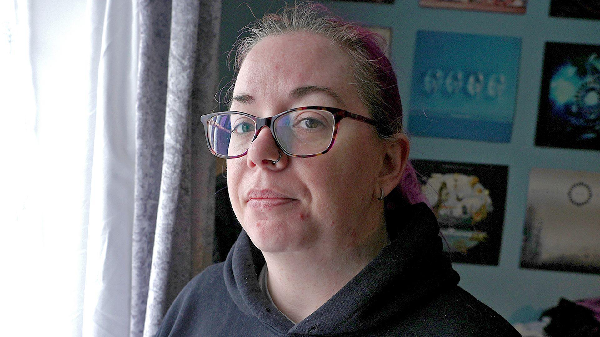 Emma wears glasses and a black hoodie.