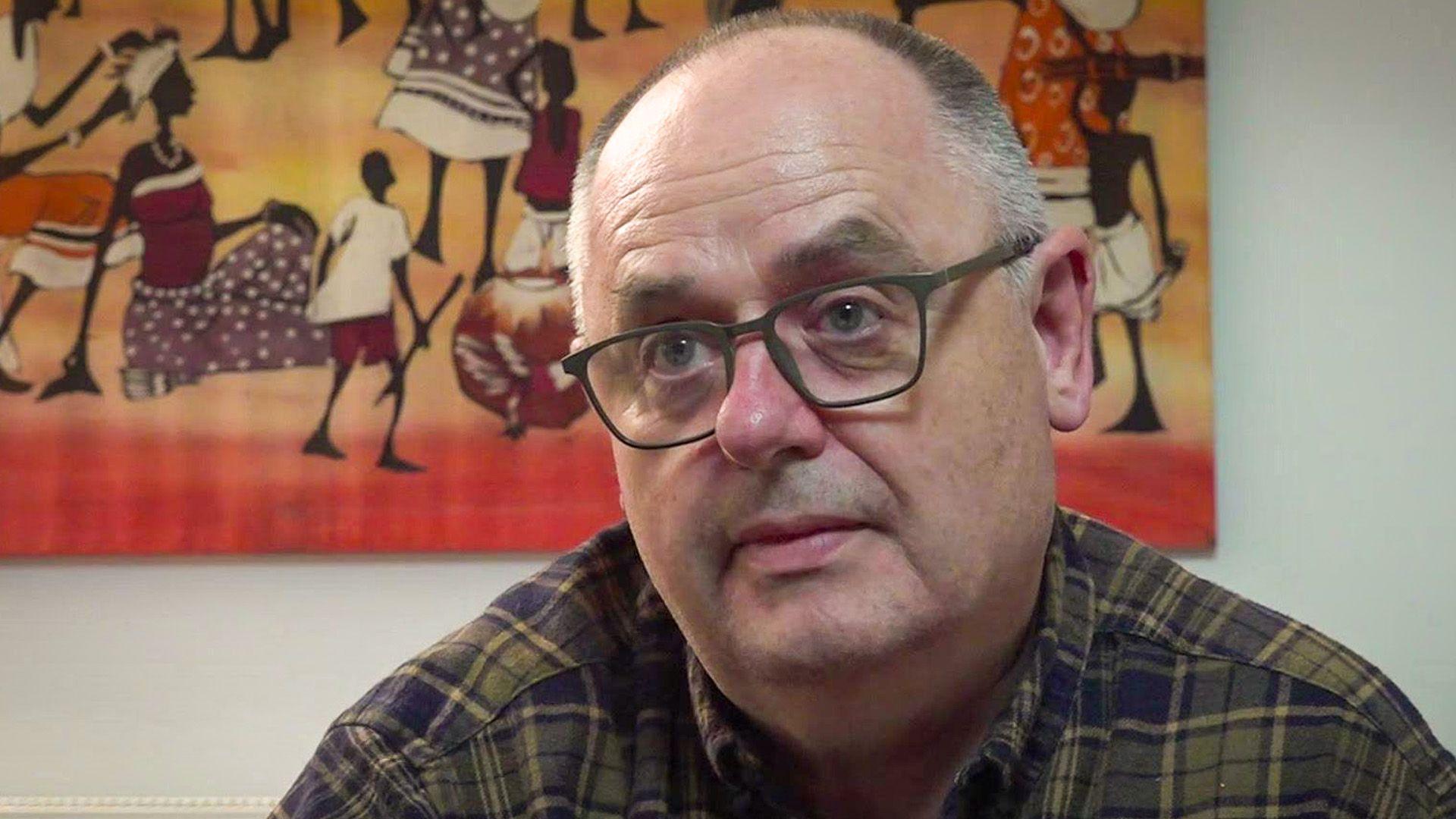 Geraint Rees yn gwisgo sbectol ac yn edrych yn ei flaen.