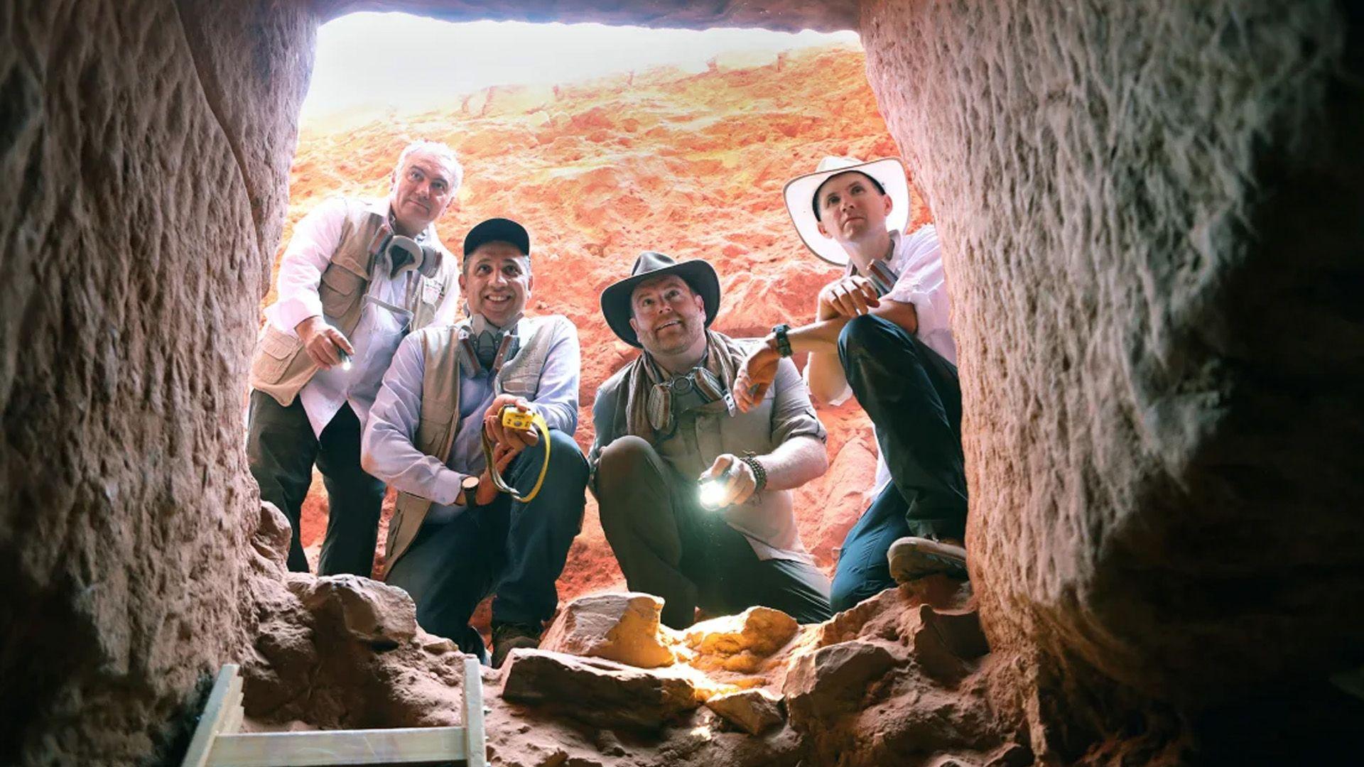 a team of archaeologists stare into a tomb