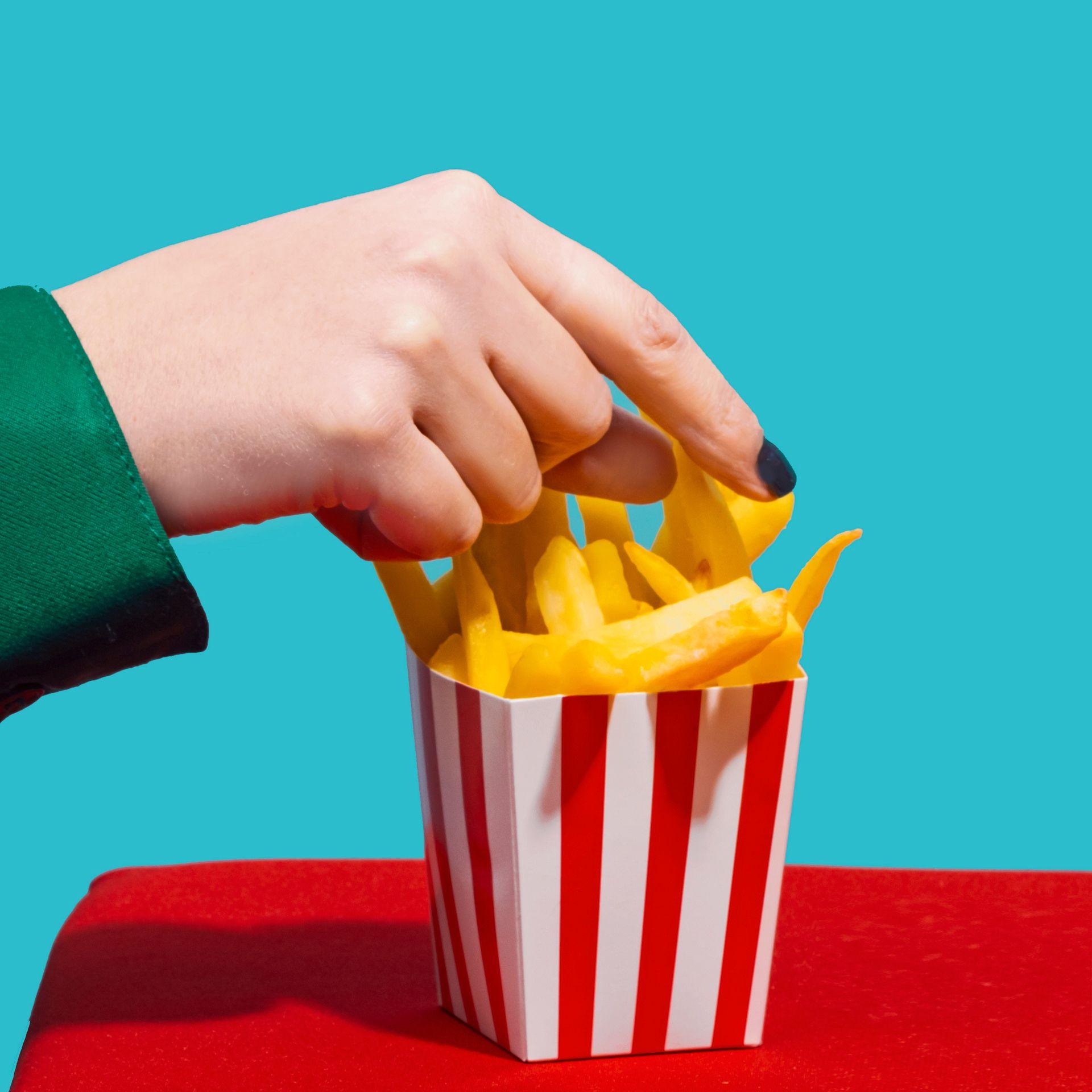 Hand picking French fries from a box